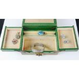 A leather clad jewellery box containing a silver bangle, an enamelled brooch in the form of a