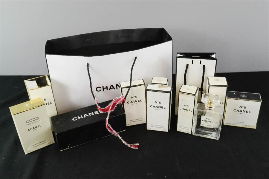 A group of Chanel boxes, paper bags and perfume bottle.