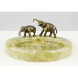 An Art Deco style agate and bronzed ashtray modelled with elephants. 18cm diameter, 8cm high.