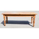 A large antique pine kitchen table, with planked top, and turned legs. 85cm wide, 198cm long, 79cm