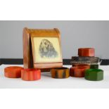 A Bakelite set of coloured napkin rings, and a cigarette case with cockerspaniel to the lid.