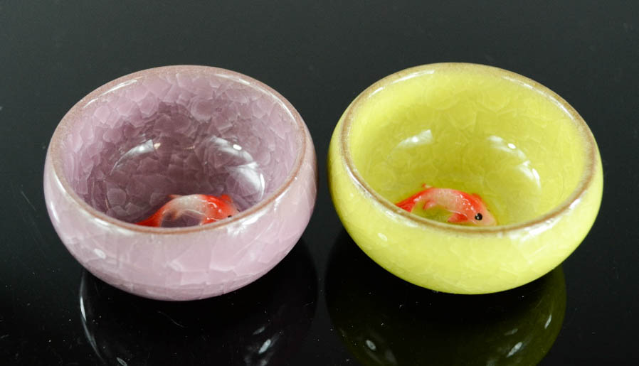 A pair of ceramic dishes modelled with goldfish to the interior, in purple and green glaze, 2½