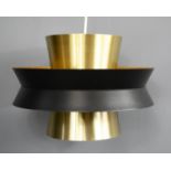 A Carl Thore pendant light, in brushed gold with central black band.