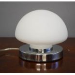 A table lamp, with white glass shade, and chrome touch sensor base.