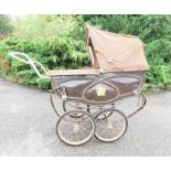 A Child's pram with faux leather hood and cover, flowers decorating the sides.