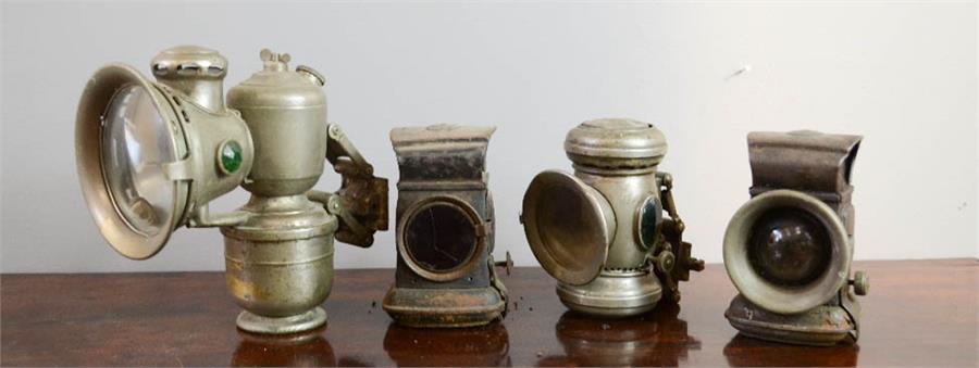 Four vintage bicycle lamps; three clip on examples with convex lenses.