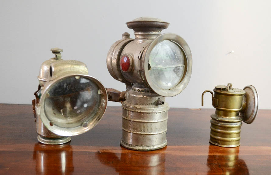 Three Vintage bicycle lamps including Premier and Mada examples.