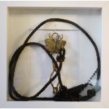 A brass Victorian skirt lifter with butterfly motif, original cord, framed.