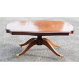 A mahogany coffee table, raised on four splayed feet with brass caps and castors.