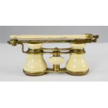 A pair of 1920s ivory opera glasses with folding ornate brass arm.