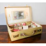 A 1930s travelling vanity case containing pink enamelled lidded containers.