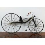 A wooden model Victorian boneshaker bicycle, painted black.