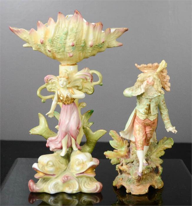 Two ceramic bisque figures, one modelled as a fairy raised on dolphins.