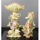 Two ceramic bisque figures, one modelled as a fairy raised on dolphins.