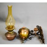 A Victorian wall mounted oil burner, the iron copper and brass bracket houses the yellow glass shade