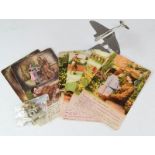 A group of WWI Postcards and cap badge, together with a model aeroplane on stand.