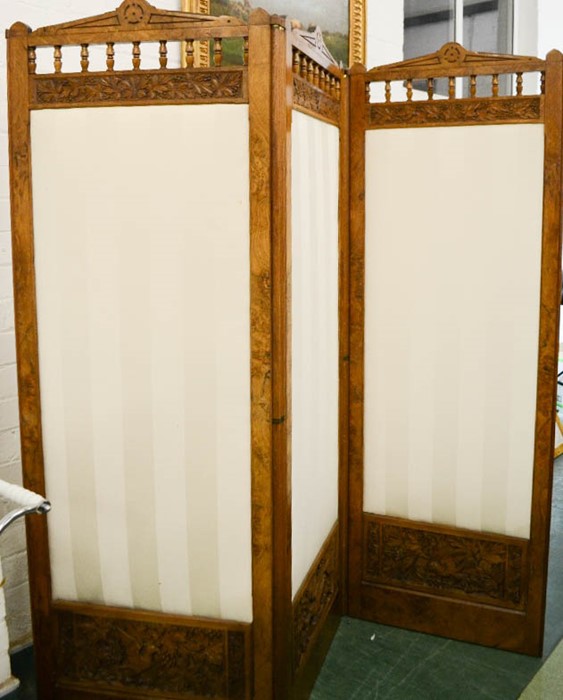 A three fold walnut carved screen, with cream upholstered panels, together with the original