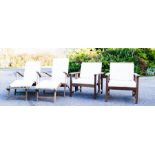 A set of teak garden furniture, two sun loungers and two chairs, all with white cushions.