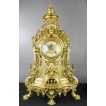 A French brass mantle clock, with enamel Roman Numerals to the dial, and cast with decorative