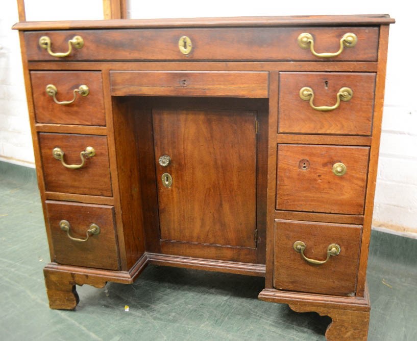 A George III mahogany kneehole desk, with recessed cupboard door flanked by drawers, 80 by 89 by