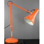 An angle poise lamp in orange.