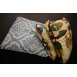 Three cushions, one in blue and white fabric, the other two depicting shoes.