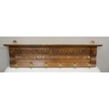 A 19th century carved continental coat rack having siz brass hooks, 116cm by 15 by 31cm.