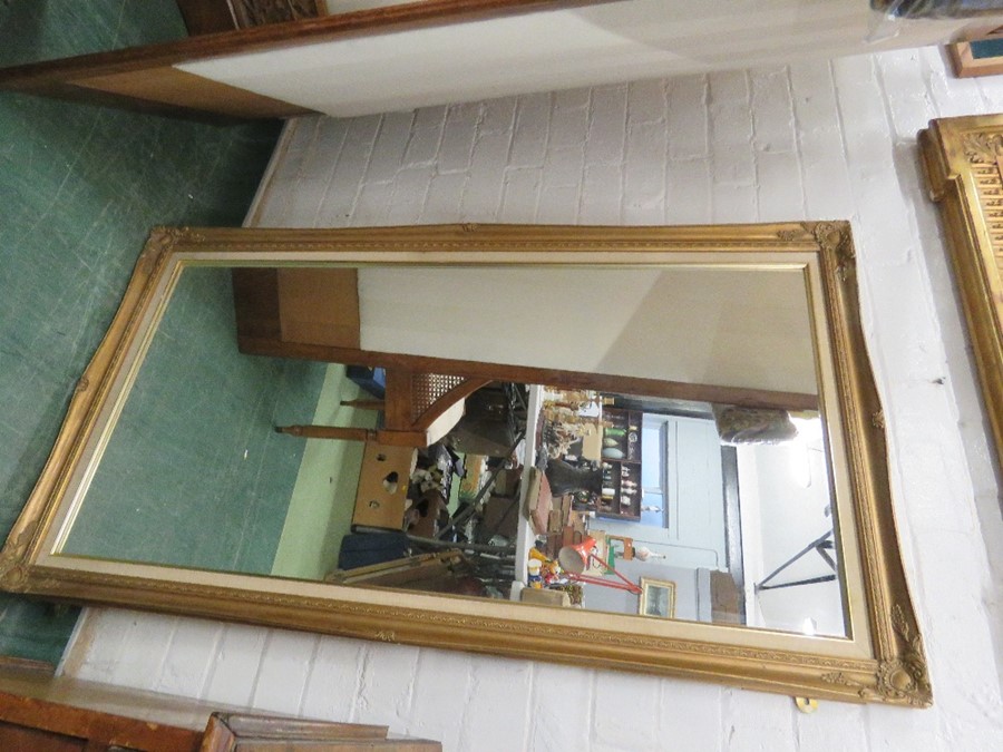 A large wall mirror, gold colored moulded decoration to the corners.