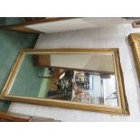 A large wall mirror, gold colored moulded decoration to the corners.