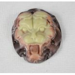 A Chinese jade carved pendant depicting a lion head.