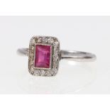 Art Deco style platinum ring set with central baguette cut ruby encircled by sixteen diamonds.