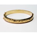 9ct gold hinged bangle, half engraved, 10.9g.