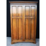 Oak two-door wardrobe by Waring & Gillows, the projected moulded cornice over fluted frieze,