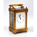 Brass carriage clock mounted by a fluted handle, chased fretwork to the frieze,