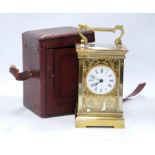 Brass carriage clock mounted by a shaped loop handle, floral chased fretwork face,