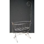 Metal work cot, the oval basket raised on splayed legs, 108cm long and 186cm high.