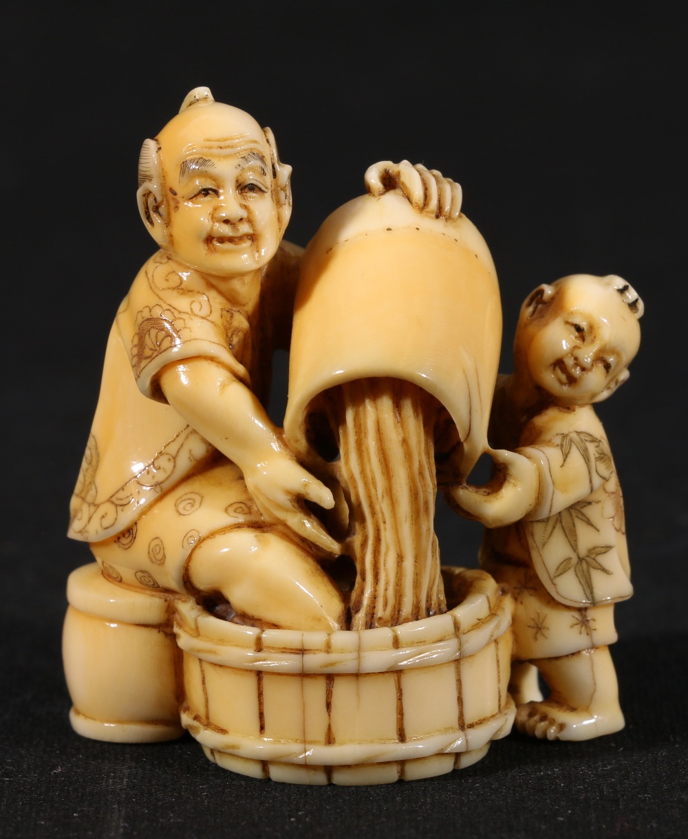 Japanese carved ivory okimono with netsuke himatoshi depicting a man and a boy pouring water into a