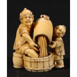 Japanese carved ivory okimono with netsuke himatoshi depicting a man and a boy pouring water into a