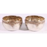 Pair of Laos silver coloured metal bowls with bands of scrolling foliage,