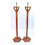 Pair of oak torchere standard lamps each with circular top raised on hexagonal columns on tripod