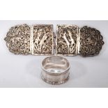 Silver belt buckle with four embossed panels, probably Indian, and a napkin ring.