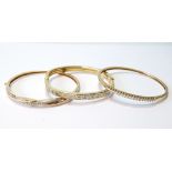 9ct gold hinged bangle with a wavy line of diamonds and two others similarly set, 36g gross.