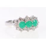 Diamond and emerald triple cluster ring with sixteen brilliants, 18ct white gold, 1974.