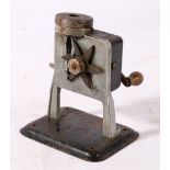 Early mechanical pencil sharpener with adjustable height lever and six bladed star wheel.