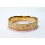 9ct gold hinged bangle, half engraved, 21g.