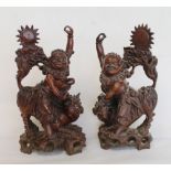 Pair of late 19th/early 20th century Oriental carved hardwood figures of two deities seated on dogs