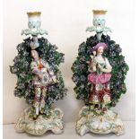 Pair of 18th century Chelsea Derby figural bocage candlesticks, he holding a cockerel,