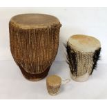 Three African tribal animal skin drums with corded decoration, 39.5cm, 27cm & 10cm high. (3).