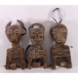 Three African carved wooden headed pulley dolls with scarification decoration, each 18cm.