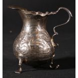 Silver cream jug of pear shape with embossed farmyard scenes, on shaped pad feet, by Benjamin West,